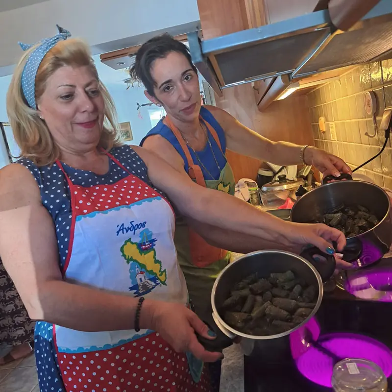 Δύο μαγείρισσες με ποδιές μπροστά σε κατσαρόλες με ντολμαδάκια