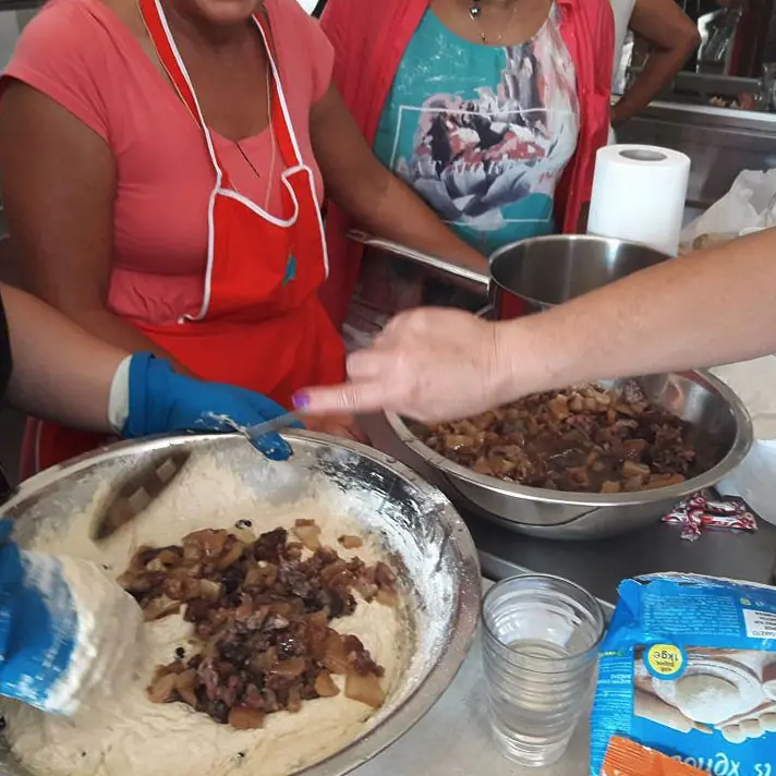 Χέρια απλώνουν γέμιση πάνω σε φύλλο ζύμης